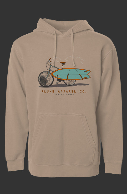 Beige hoodie with a graphic of a bicycle carrying a surfboard and 'Fluke Apparel Co.' text on a gray background.