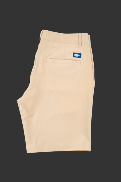 Beige shorts with a blue logo tag on a white background