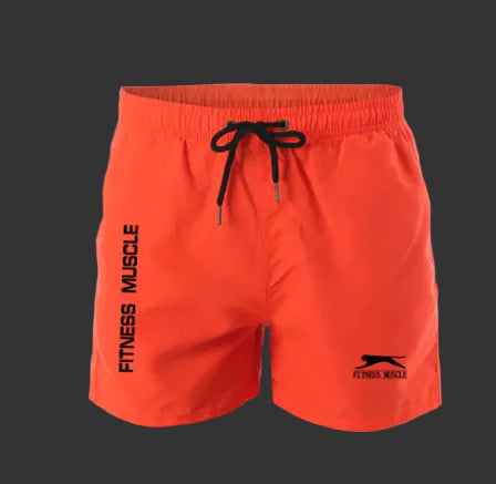 Orange shorts with black drawstring and 'Fitness Muscle' branding on a gray background.
